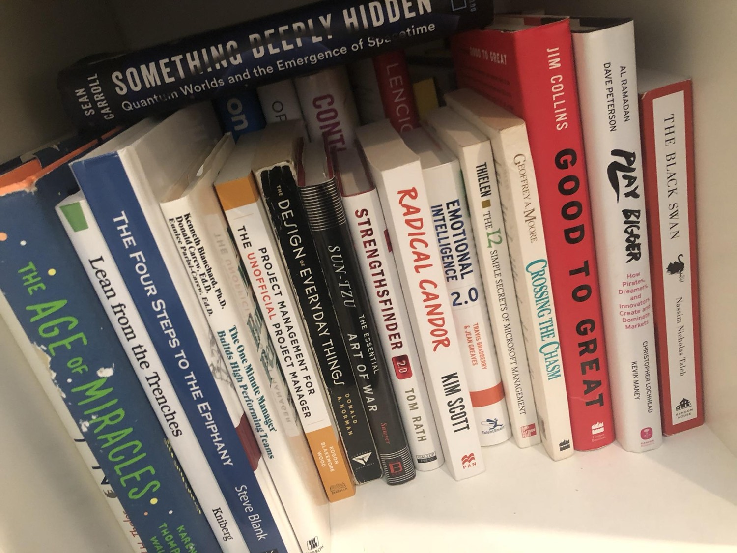 A shelf of team-building and strategy books, including Good to Great, Radical Candor, StrengthsFinder, Crossing the Chasm, and The Four Steps to the Epiphany